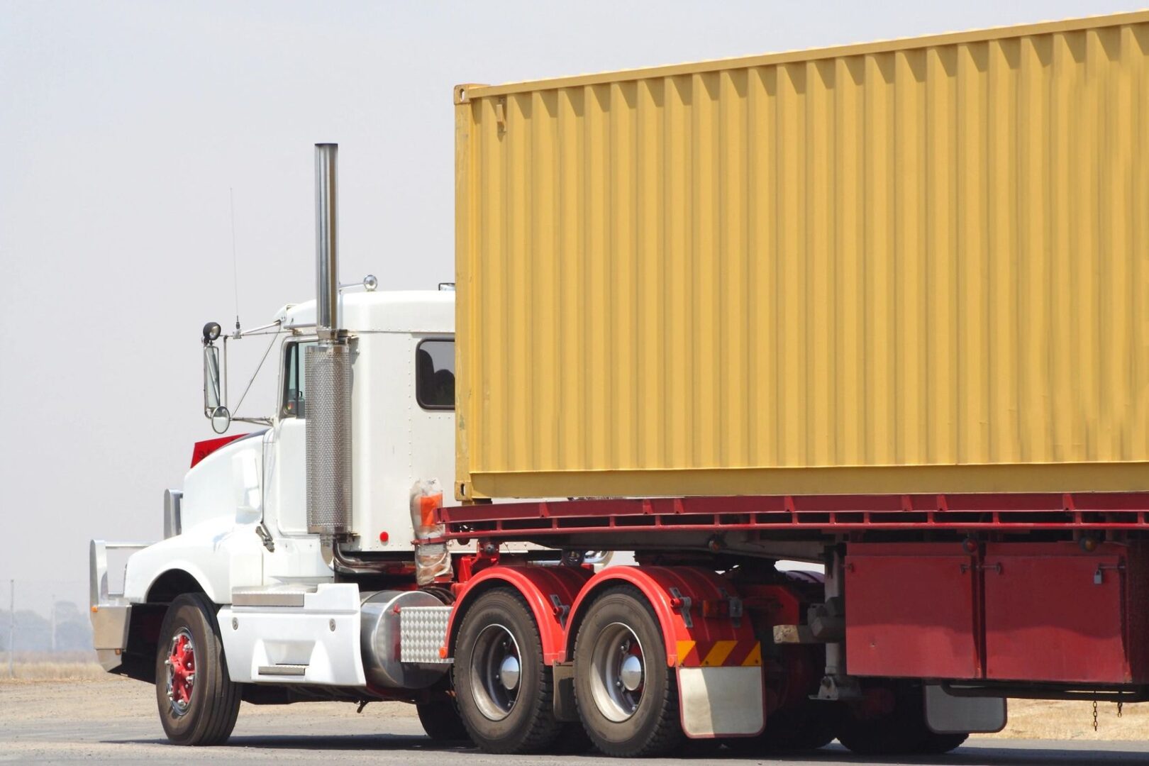 A semi truck with its trailer parked on the side of the road.