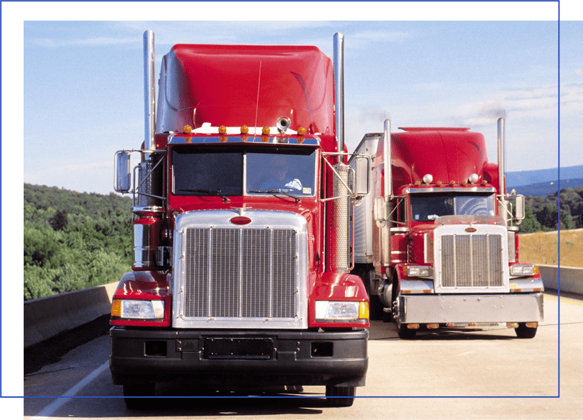 Two red trucks are parked on the side of a road.